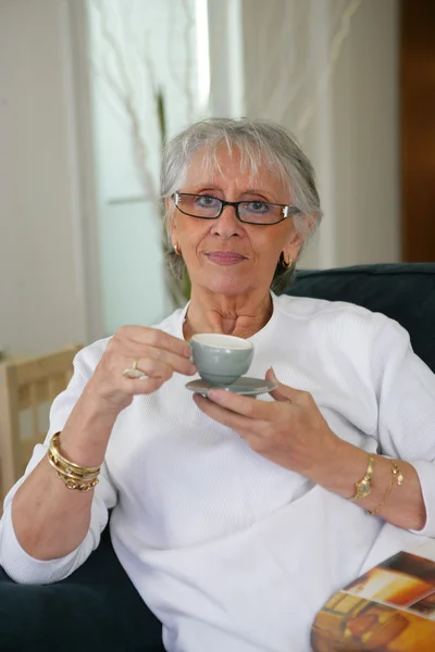 Старшая женщина пьет кофе дома — стоковое фото