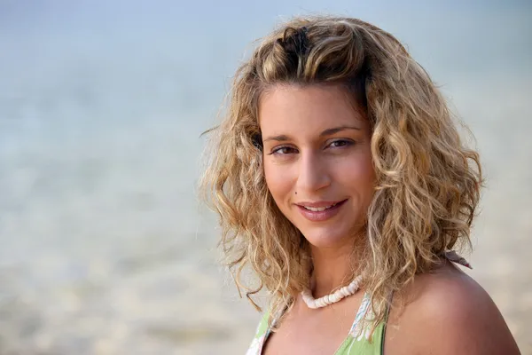 Curly-haired blond kvinna på stranden — Stockfoto