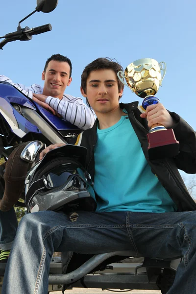 Um homem com uma moto e um troféu . — Fotografia de Stock