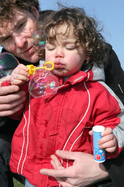 Delicioso niño pequeño con papá haciendo burbujas de jabón — Foto de Stock