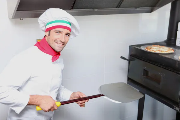 Um cozinheiro de pizza na frente de um forno — Fotografia de Stock