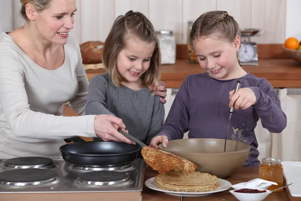 Mujer cocinando crepes con sus hijas —  Fotos de Stock