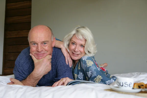 ベッドで朝食を楽しんでいる年配のカップル — ストック写真