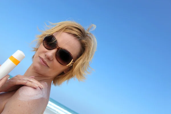 Frau trägt Sonnencreme auf ihre Schulter auf — Stockfoto