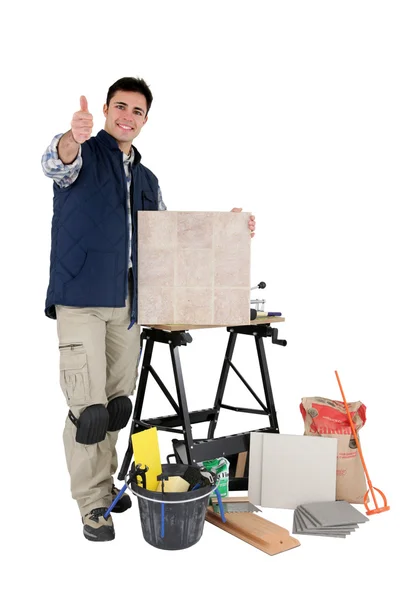 Aprovação comerciante posando com suas ferramentas e materiais de construção — Fotografia de Stock