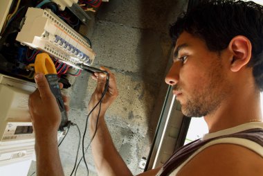 Electrician taking reading from fuse box clipart