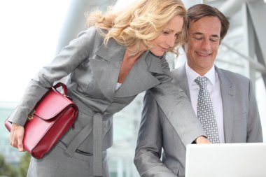 Business couple looking at laptop clipart