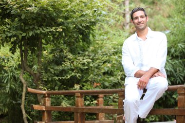 Man sitting on a Japanese style wooden fence clipart