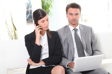 Businesscouple working in waiting area clipart