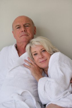 Retired couple sat in bathing robes clipart