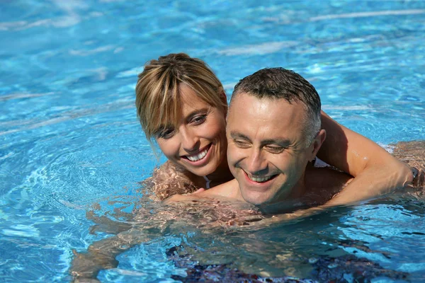 Couple swimming in hotel pool — Stok fotoğraf