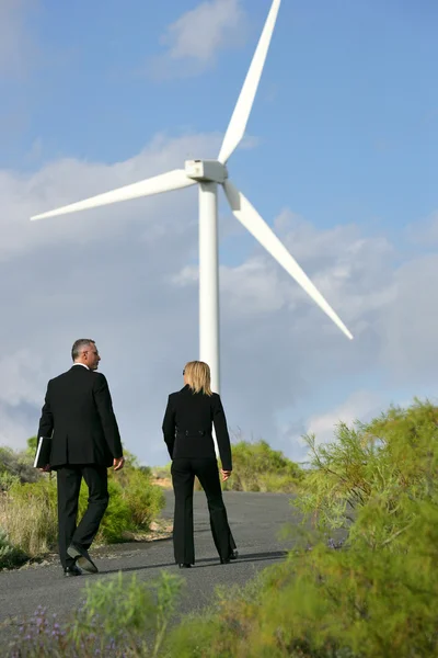 Homme et femme en costume marchant à côté d'une éolienne — Photo