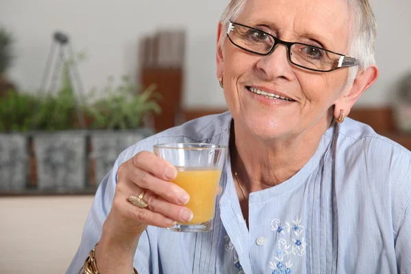 Kvinna som dricker ett glas apelsinjuice — Stockfoto