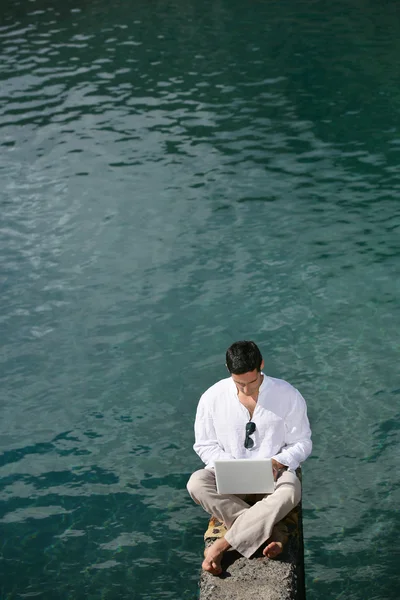 Hombre con portátil cerca de un lago — Foto de Stock