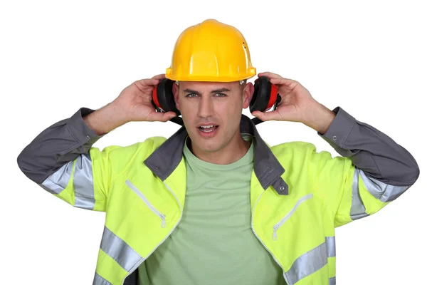 Constructor con casco quitando orejeras — Foto de Stock