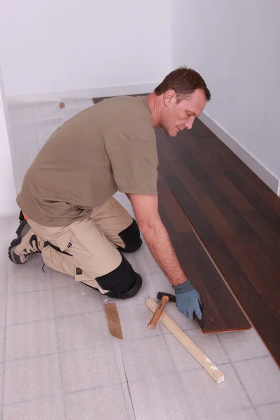 Homem em casa que estabelece piso de madeira — Fotografia de Stock