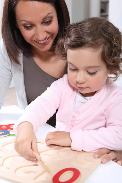 Mother and daughter doing a wooden — Stock Photo, Image