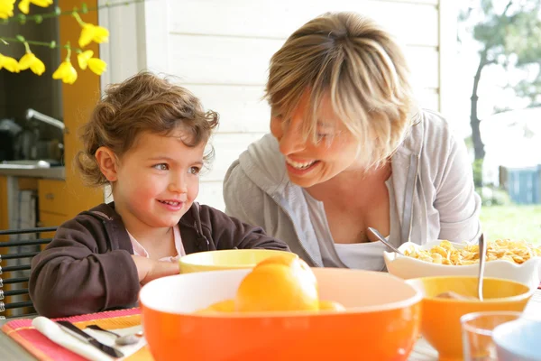 Little girl having breakfast on patio with mother — Stock Photo, Image