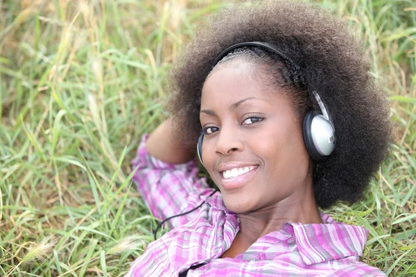 Femme posée sur l'herbe écoutant de la musique — Photo