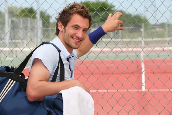Tennis player leaning against fence — Stock Photo, Image