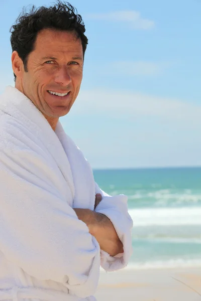 Man n dressing gown stood on beach — Stock Photo, Image
