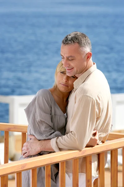 Középkorú pár állt a tengerre néző erkéllyel — Stock Fotó