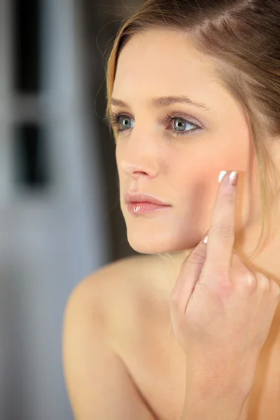 Mladá žena použitím obličejové krém — Stock fotografie