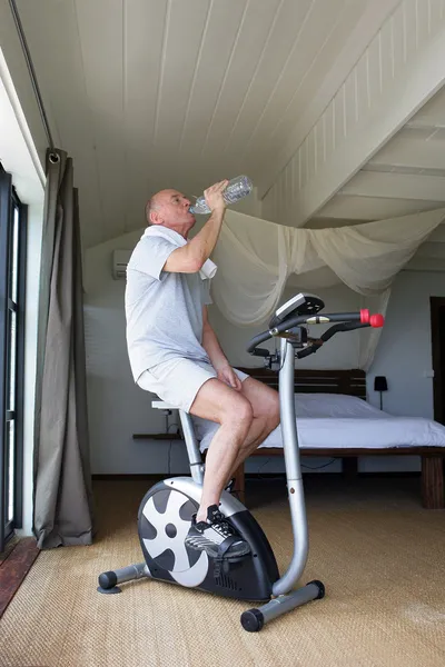 Man cycling on machine at home — Stock Photo, Image