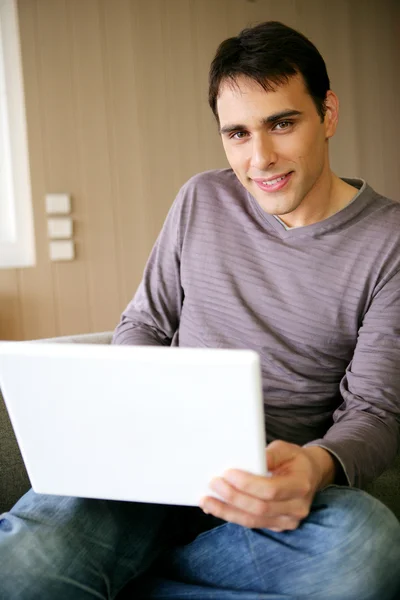 Uomo seduto a casa con un computer portatile — Foto Stock