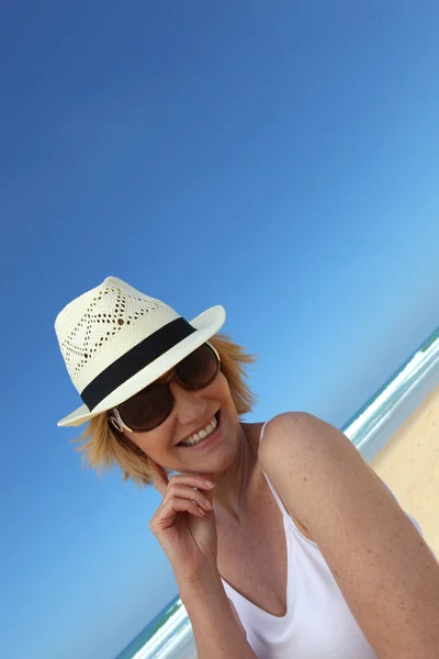 Frau am Strand mit Hut und Sonnenbrille — Stockfoto