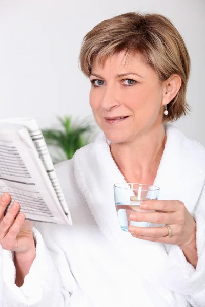 Vrouw in badjas krant lezen — Stockfoto