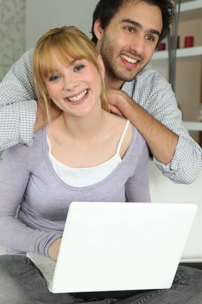 年轻夫妇在家中使用一台笔记本电脑 — 图库照片