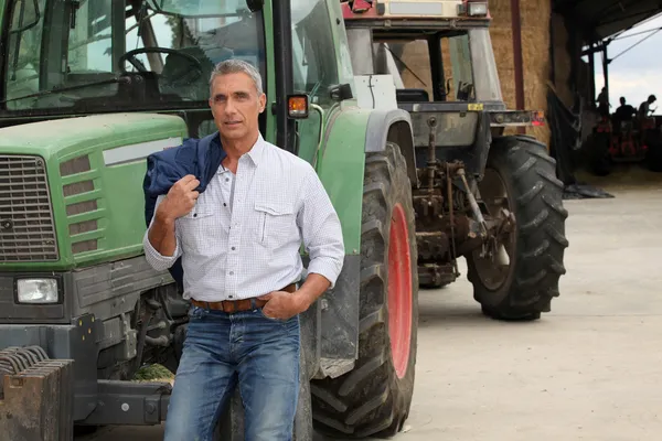 Bonde poserar nära traktorer — Stockfoto