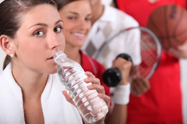 Sportig unga flickan dricka buteljerat vatten med andra ung sport i — Stockfoto