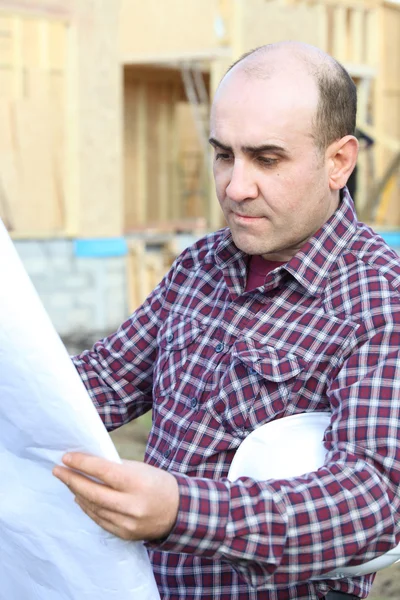 Housebuilder looking at plans on site — Stock Photo, Image