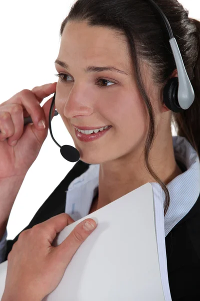 Mujer sonriente usando un auricular y sosteniendo un cuaderno — Foto de Stock