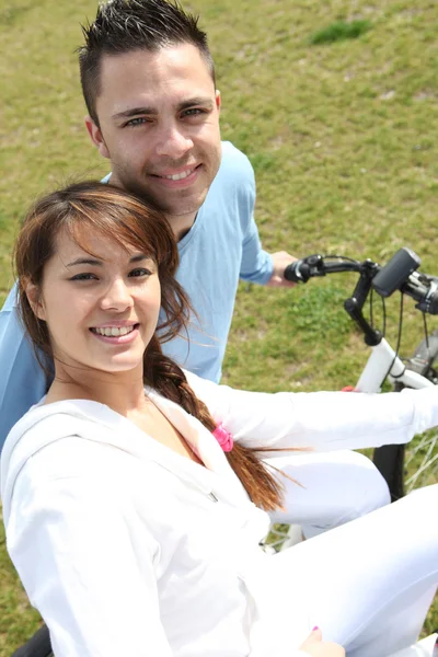 Jovem casal andar de bicicleta em um parque — Fotografia de Stock