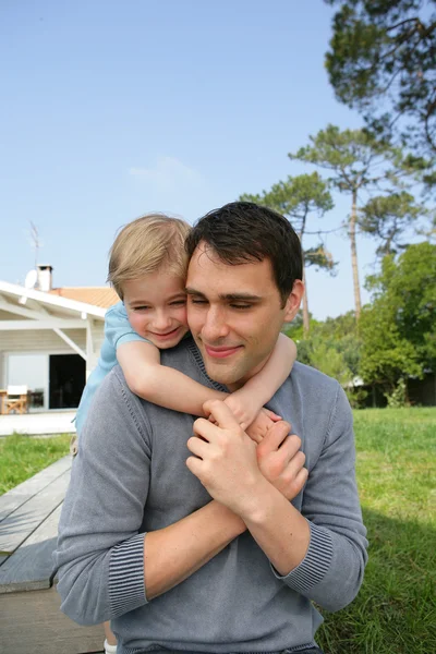 Dad stood in front yard giving daughter a piggy-back — Stock Photo, Image