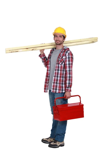 Carpinteiro transportando pranchas de madeira e caixa de ferramentas — Fotografia de Stock