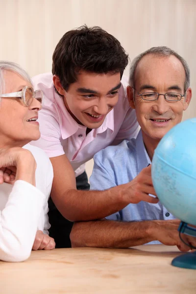 Far-och morföräldrar ant deras barnbarn tittar på en jordglob — Stockfoto