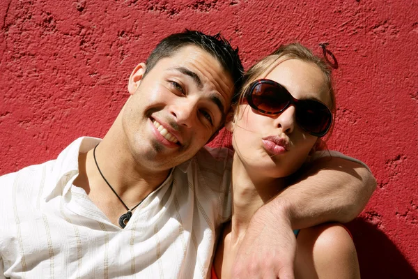 Casal legal posando contra uma parede vermelha — Fotografia de Stock