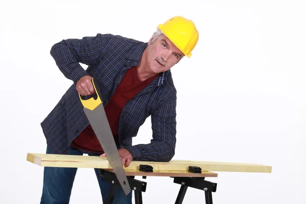 Artesano cortando una tabla con una sierra — Foto de Stock