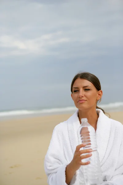 Esmer su şişe tutan bir sahilde duran — Stok fotoğraf