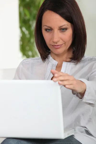 Frau arbeitet drinnen am Laptop — Stockfoto
