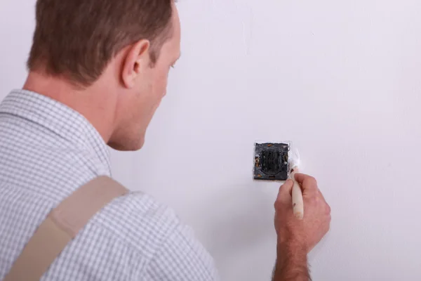 Man painting around a plug — Stock Photo, Image