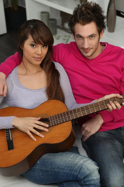 Пара, играющая дома на гитаре — стоковое фото