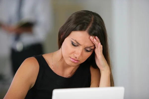 Frau mit Kopfschmerzen am Laptop — Stockfoto