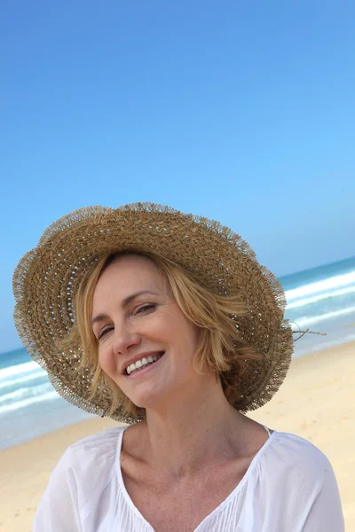 微笑着一顶草帽在海滩上的女人 — 图库照片