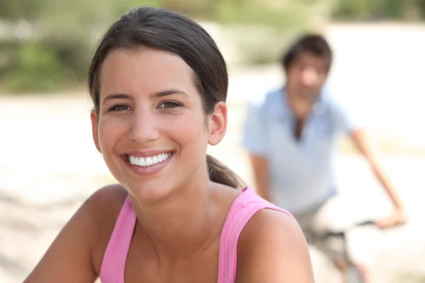 バック グラウンドで自転車に乗る男に笑みを浮かべて女性 — ストック写真