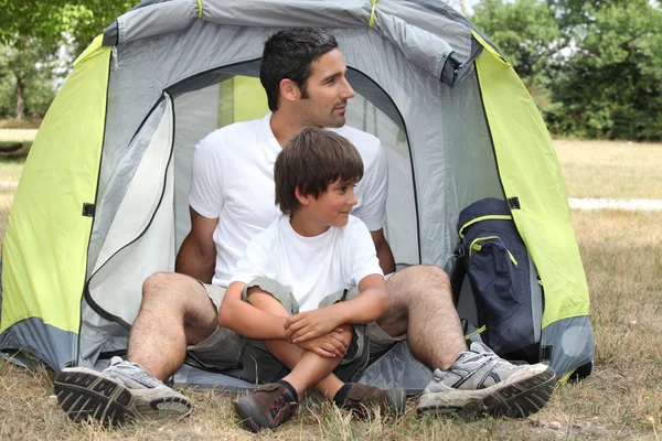 Отец и сын сидят у палатки — стоковое фото